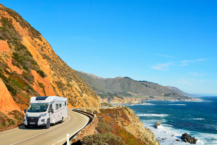 camping-car profilé Pilote roulant sur une route de bord de mer