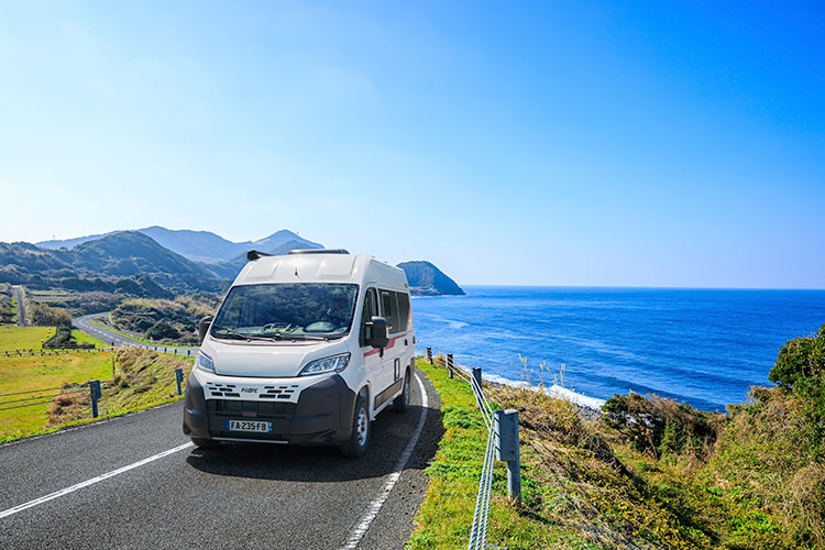 Vue de face d'un fourgon aménagé Pilote roulant au bord de mer
