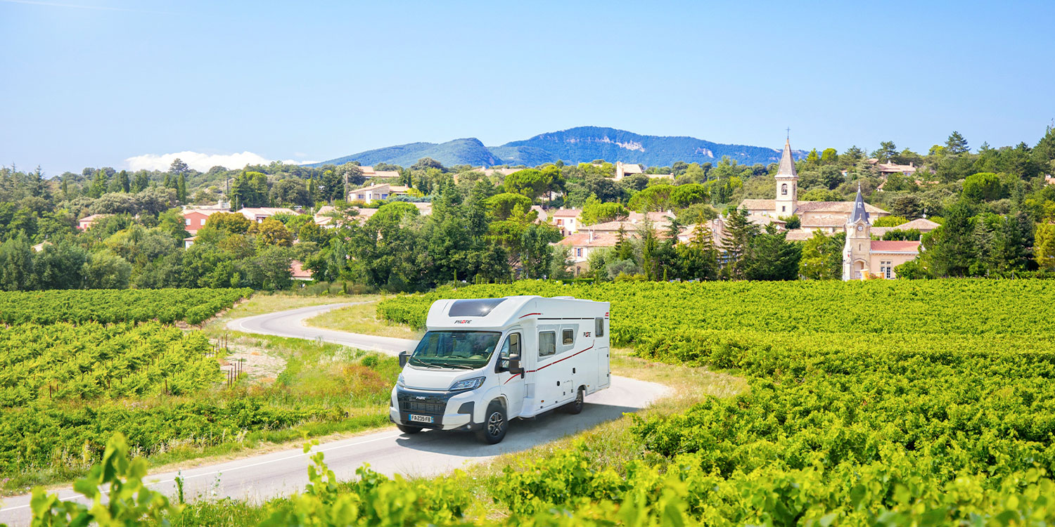 camping-car profilé Pilote roulant sur une route avec des vignes de chaque côté