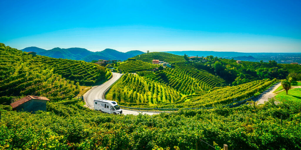 camping-car profilé Pilote roulant sur une route entouré de vignes