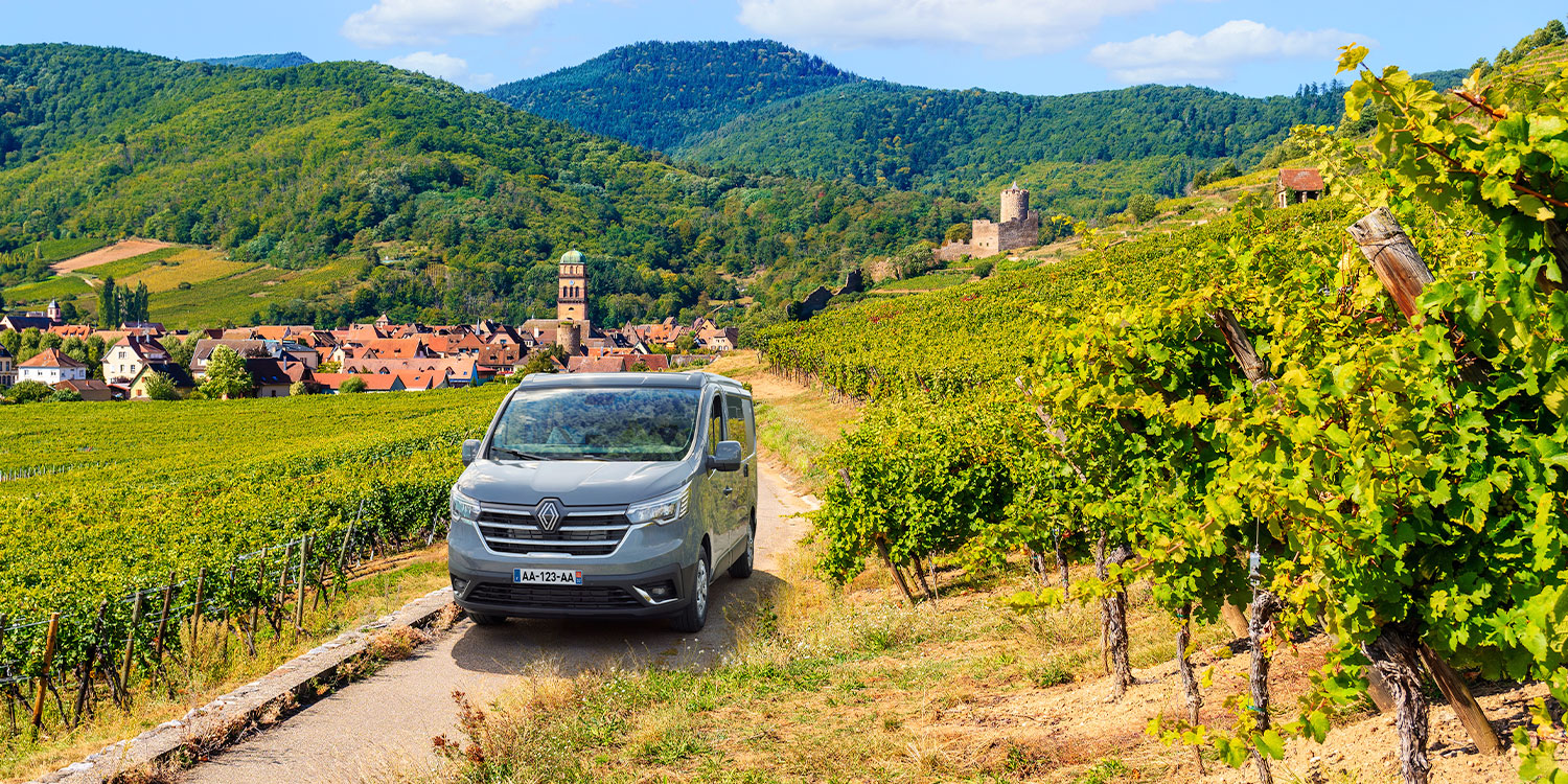 Van aménagé Pilote roulant sur une route le long de vignes