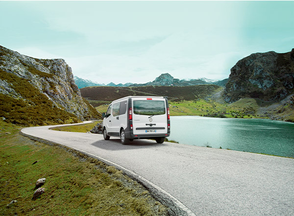 Van aménagé Pilote roulant au bord d'un lac en montagne. 